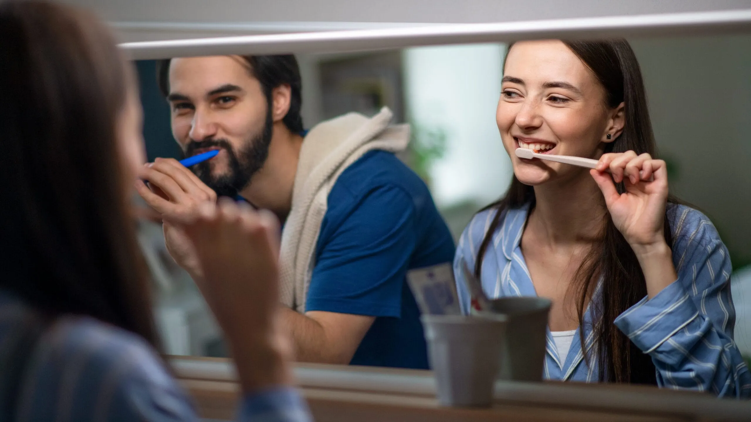 man an woman smiling while getting their tooth brushed