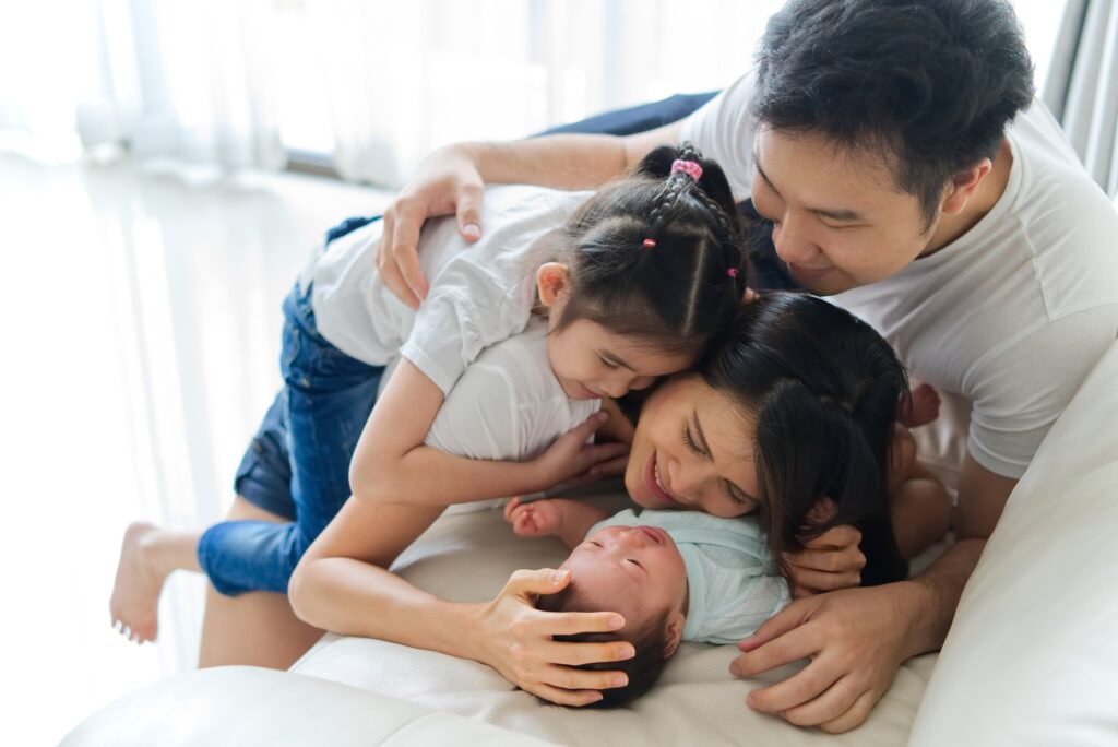 Happy family at home. Asian father, mother and sister on sofa are smiling.